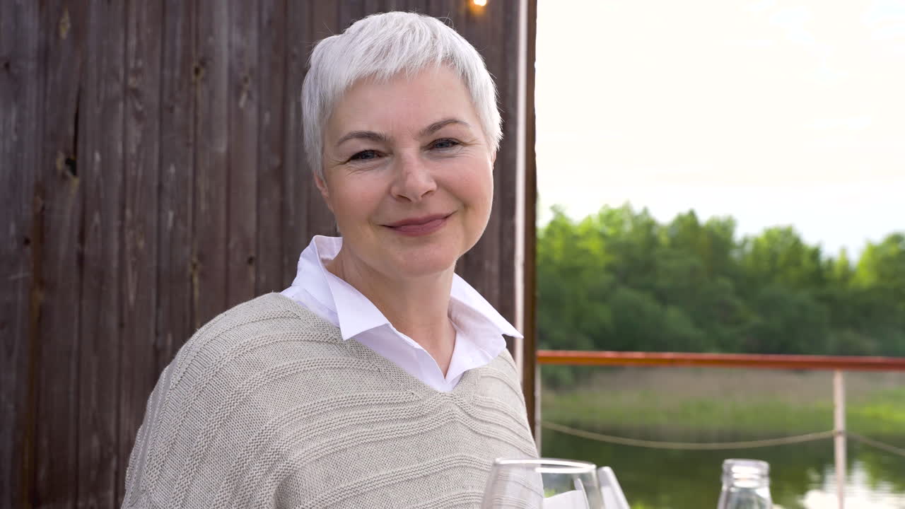Portrait of a senior woman drinking a glass of wine and smiling. She's outdoors.