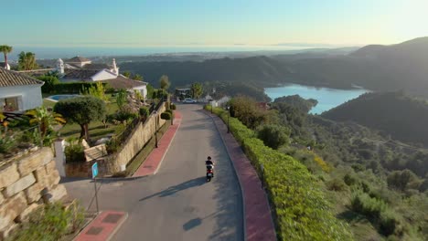 person driving down luxury district hill with majestic view on scooter