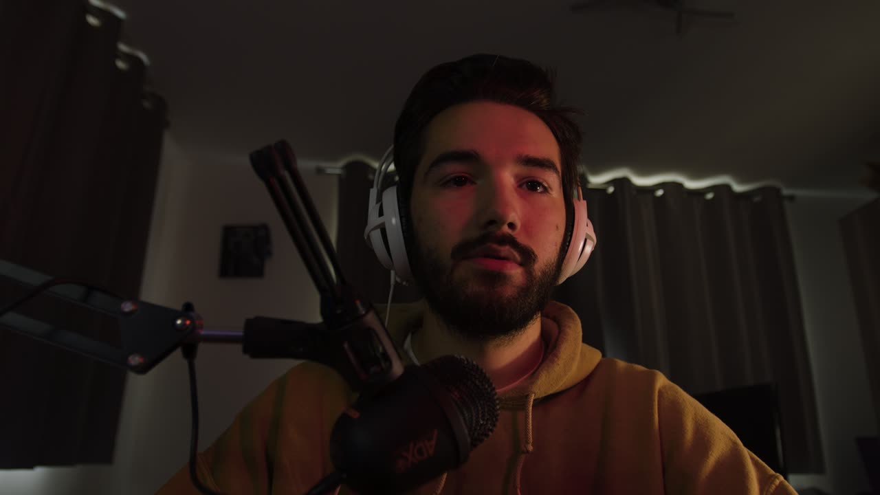 hombre jugando en una pc hablando en el micrófono sonriendo, asintiendo con la cabeza y levantando las cejas