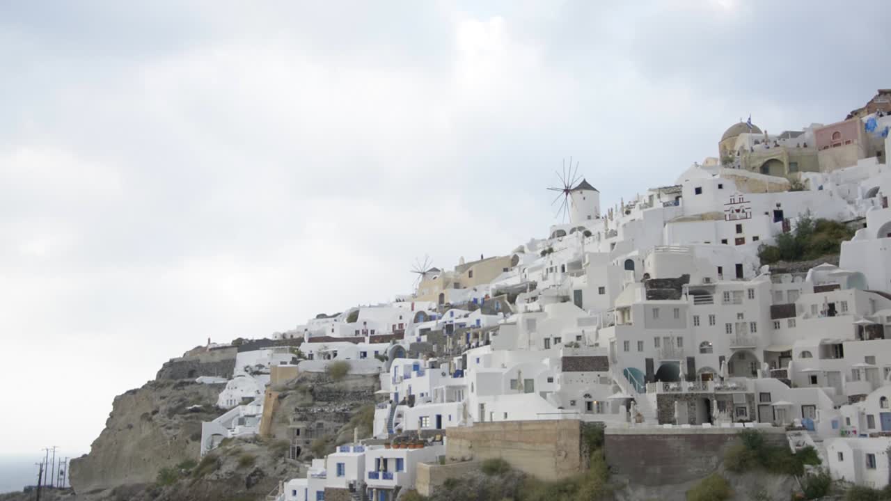 la icónica ciudad de oia en santorini, grecia, con sus molinos de viento y sus impresionantes edificios blancos a lo largo de la caldera