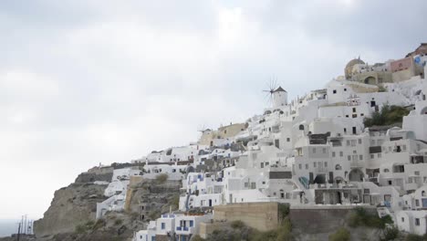 la icónica ciudad de oia en santorini, grecia, con sus molinos de viento y sus impresionantes edificios blancos a lo largo de la caldera