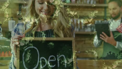 animation of macro covid-19 cells floating over happy caucasian female chef holding open sign