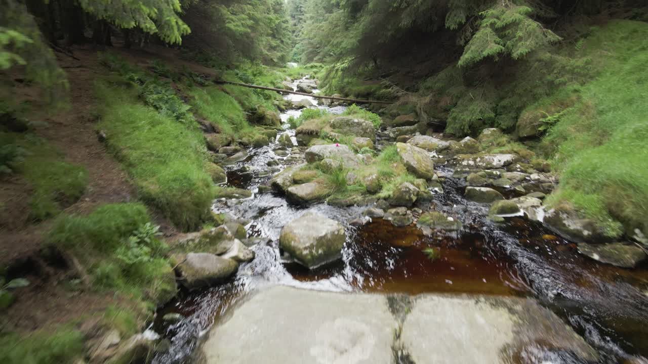 Naturskøn udsigt over tørvefarvet vandløb, der strømmer gennem klipperne i Wicklow-bjergene i Irland – lavt luftfoto