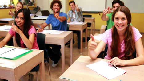 estudiantes sonriendo y dando pulgares hacia la cámara en el aula