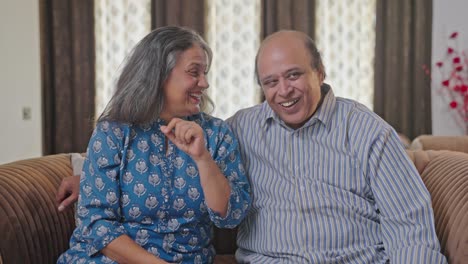 Happy-Indian-old-couple-watching-TV