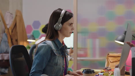 joven mujer de negocios caucásica usando la computadora navegando en línea trabajando en un proyecto de redes escuchando música disfrutando de la oficina de inicio de moda