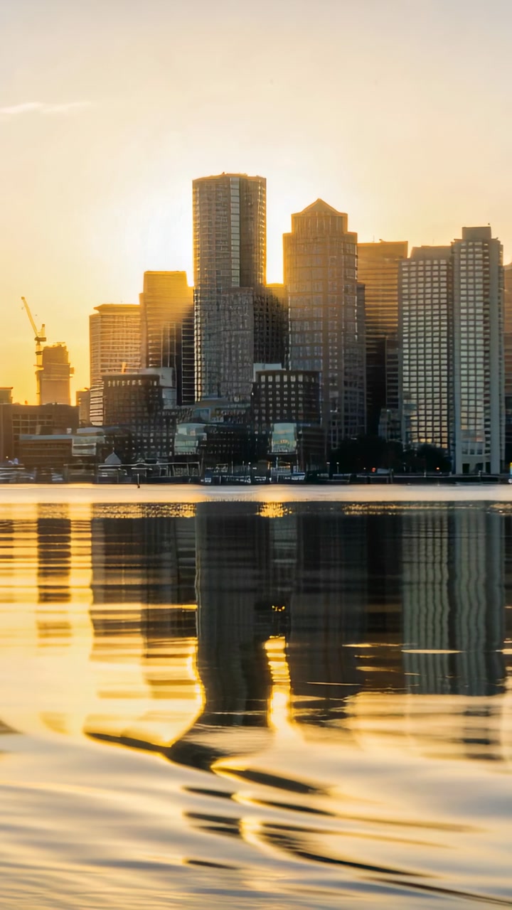 Vertical video: City skyline brightening as sunrise peeking, towers and crane reflecting on water