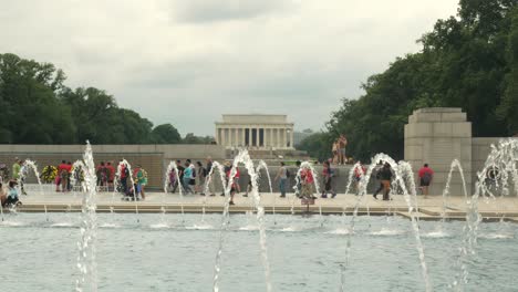 lincoln memorial neoclassical temple with tourists and water fountain in foreground, washington, d.c., pan up reveal slow motion
