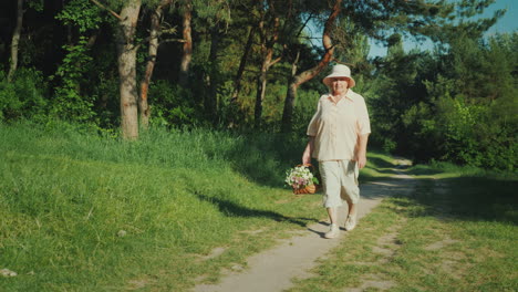 Eine-ältere-Frau-Geht-Einen-Waldweg-Entlang-Und-Trägt-Einen-Korb-Mit-Wildblumen