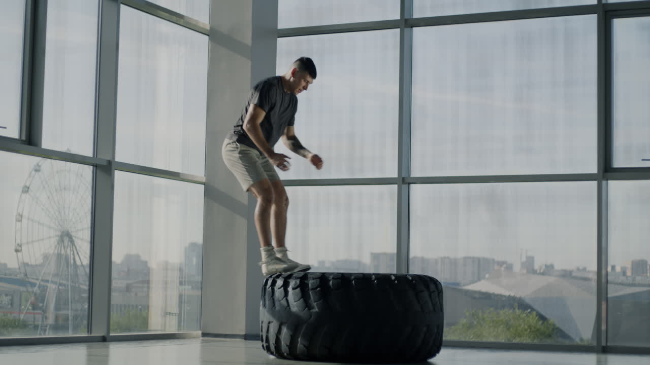 Man Performing Tire Jumps in Gym
