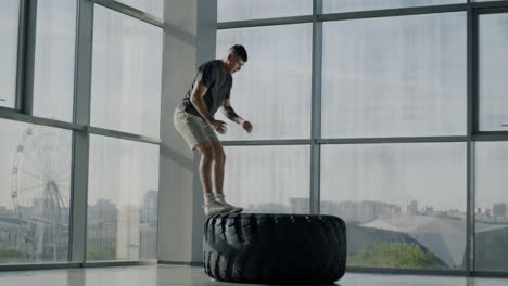 man performing tire jumps in gym