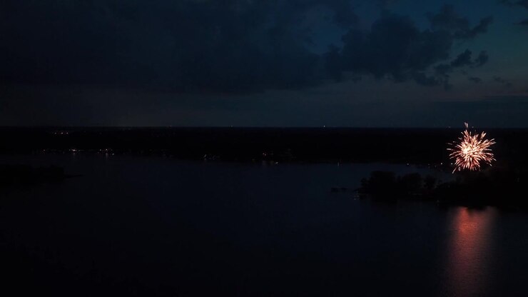 Ampia ripresa aerea panoramica di uno spettacolo pirotecnico durante un temporale con fulmini su un lago del Minnesota di notte. 4K.