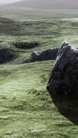 a scenic view of a grassy field with rocks and hills in the distance