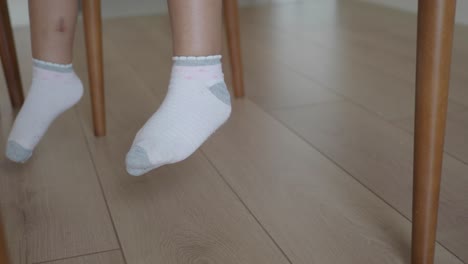los pies del niño en calcetines colgando de una silla