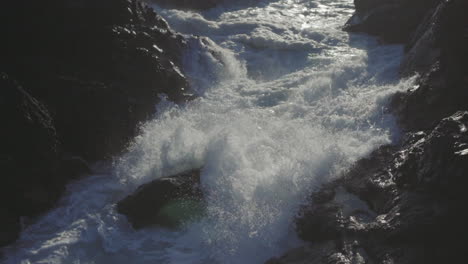 Slow-motion-close-up-shot-of-an-ocean-wave-smashing-on-rocks-and-splashing