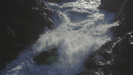 Tiro-De-Cerca-En-Cámara-Lenta-De-Una-Ola-Oceánica-Rompiendo-Rocas-Y-Salpicando