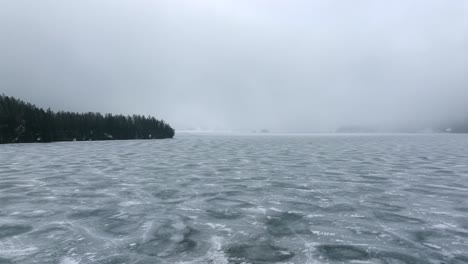 Drone-flight-over-a-frozen-lake-in-Switzerland-as-the-snow-storm-slowly-rolling-into-the-Engadin-Valley