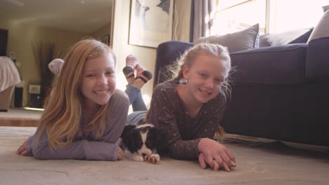 Portrait of two young girls looking at the camera, while their adorable puppy.