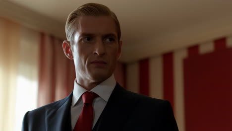portrait of a man in a dark suit with a red tie