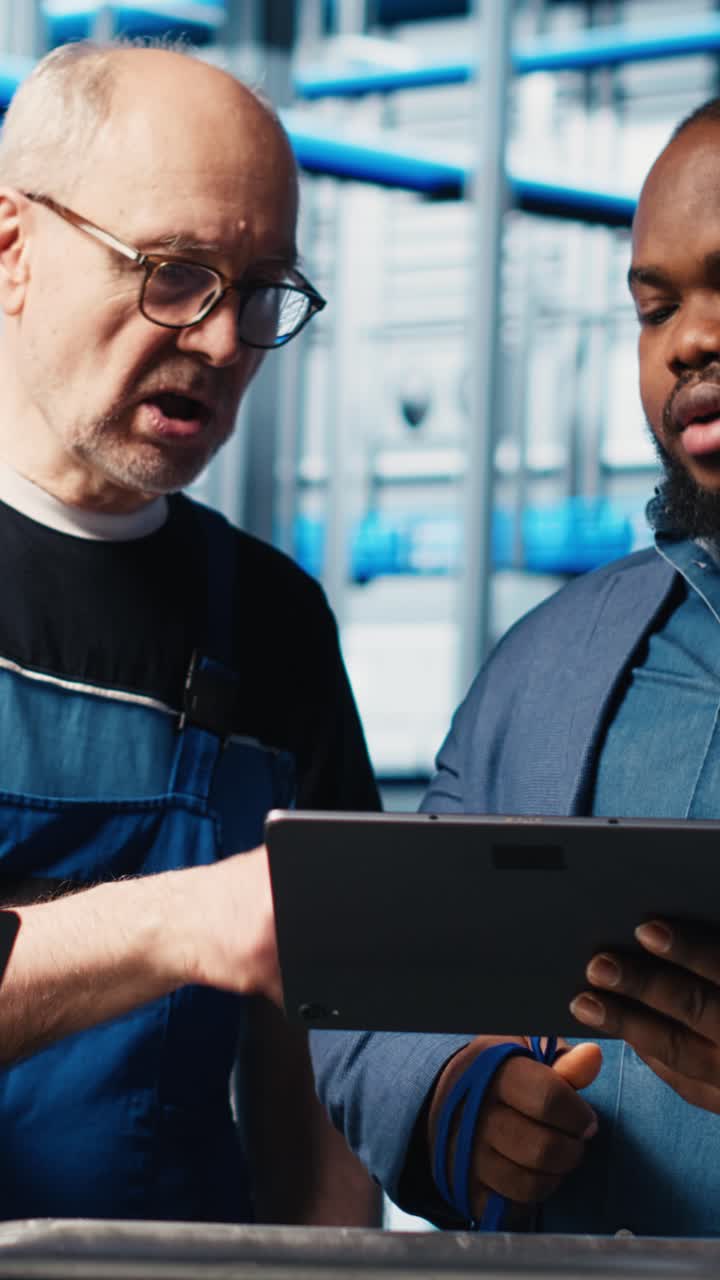 Vertical video Engineers talk with manager overseeing smart factory, showing collected metrics