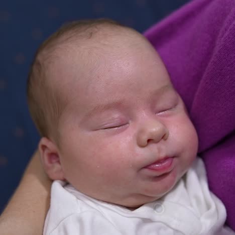 cute child sleeping sweetly and pressing his tiny lips in his sleep. adorable baby boy is resting peacefully in his mother's hands. close up