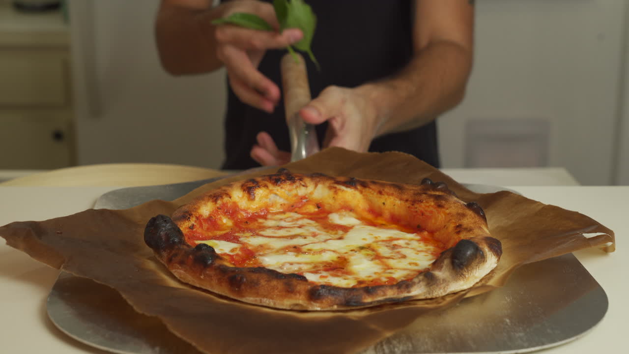 Pizzaiolo che serve la più deliziosa pizza Margherita napoletana, completandola con basilico fresco