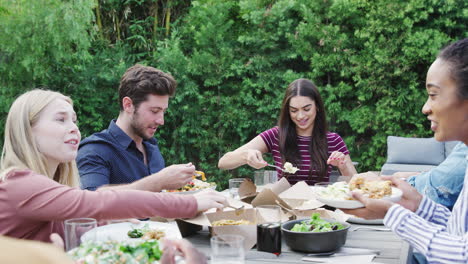 Amigos-Multiculturales-En-Casa-Sentados-A-La-Mesa-Disfrutando-De-La-Comida-En-La-Fiesta-De-Verano-En-El-Jardín