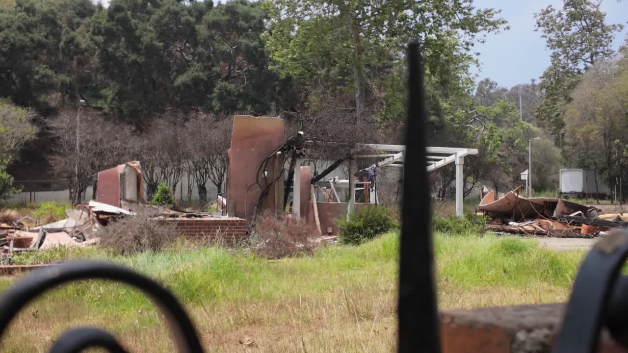 Gimbal close-up panning shot of a burned property after the wildfire in Pacific Palisades, California. 4K