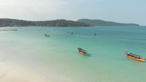 Aguas-Paradisíacas-Poco-Profundas-De-La-Bahía-Sarracena-Pobladas-Por-Barcos-De-Pesca-De-Madera,-Lugareños-Y-Turistas-En-Koh-Rong-Sanloem,-Camboya---Sobrevuelo-Aéreo-De-ángulo-Bajo