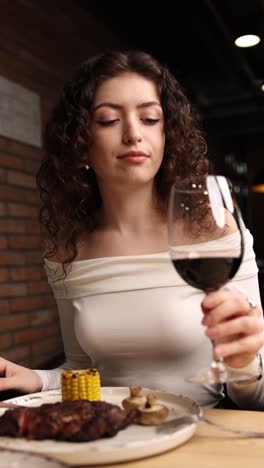 woman enjoying a glass of red wine and a delicious meal