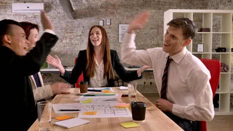 business team of 4 mixed race people holding meeting in modern office, caucasian woman talking, everyone cheering and exciting