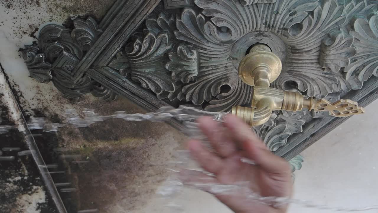 Person washing hands at a historical water fountain