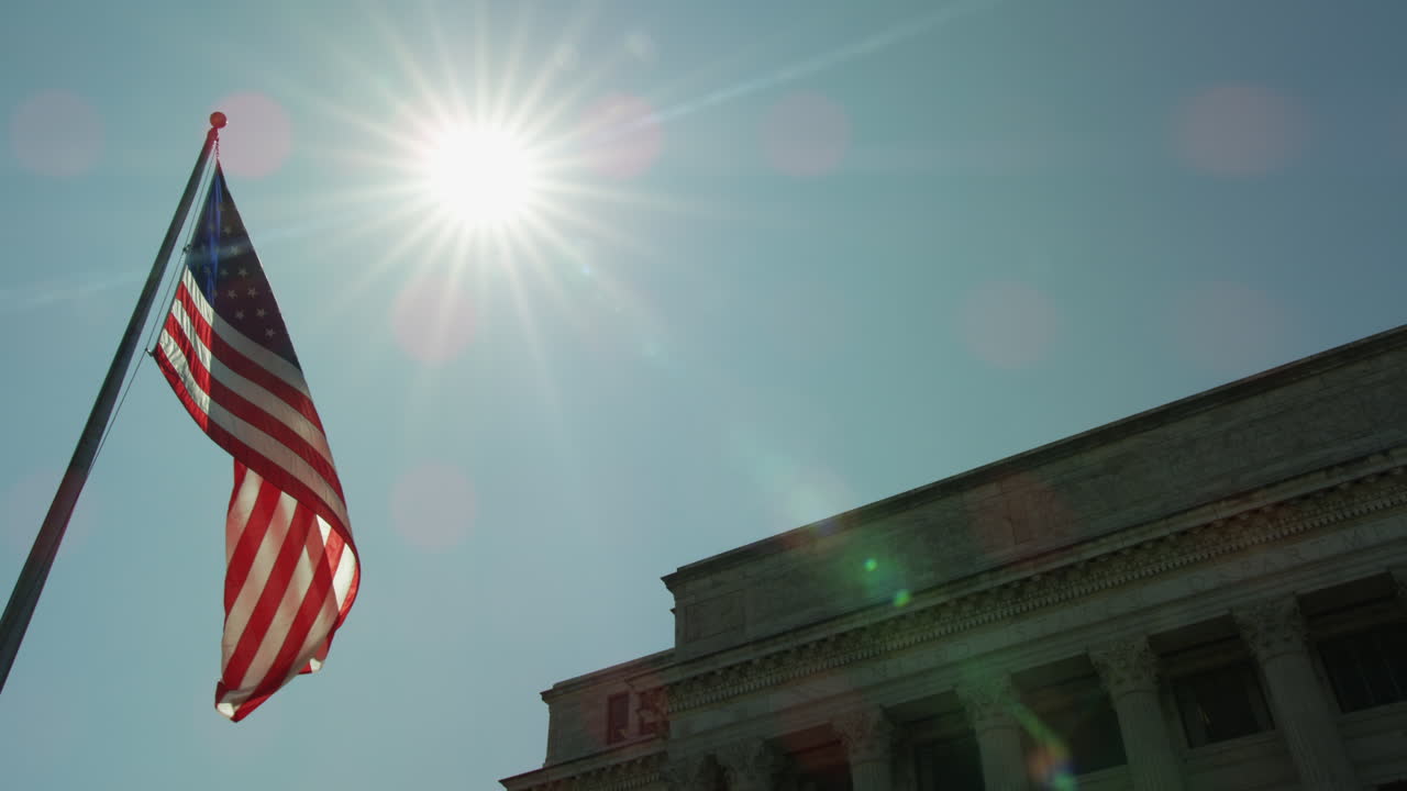American Flag waving in front of Washington DC building on sunny day.