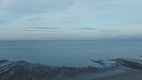 tomada aérea de un dron volando sobre una playa y hacia el mar en la bahía de tasmania, nueva zelanda
