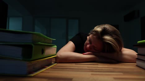 exhausted person sleeping at a desk with binders