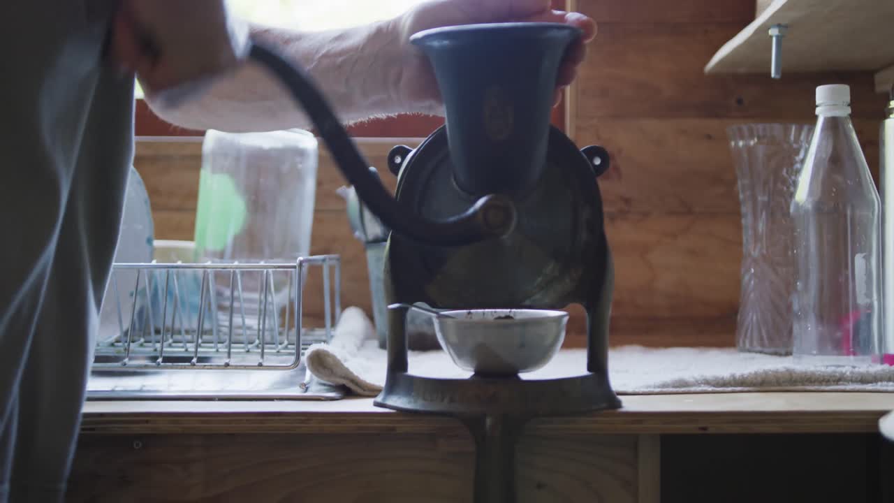 hombre caucásico mayor preparando café en el molinillo de café en la cocina