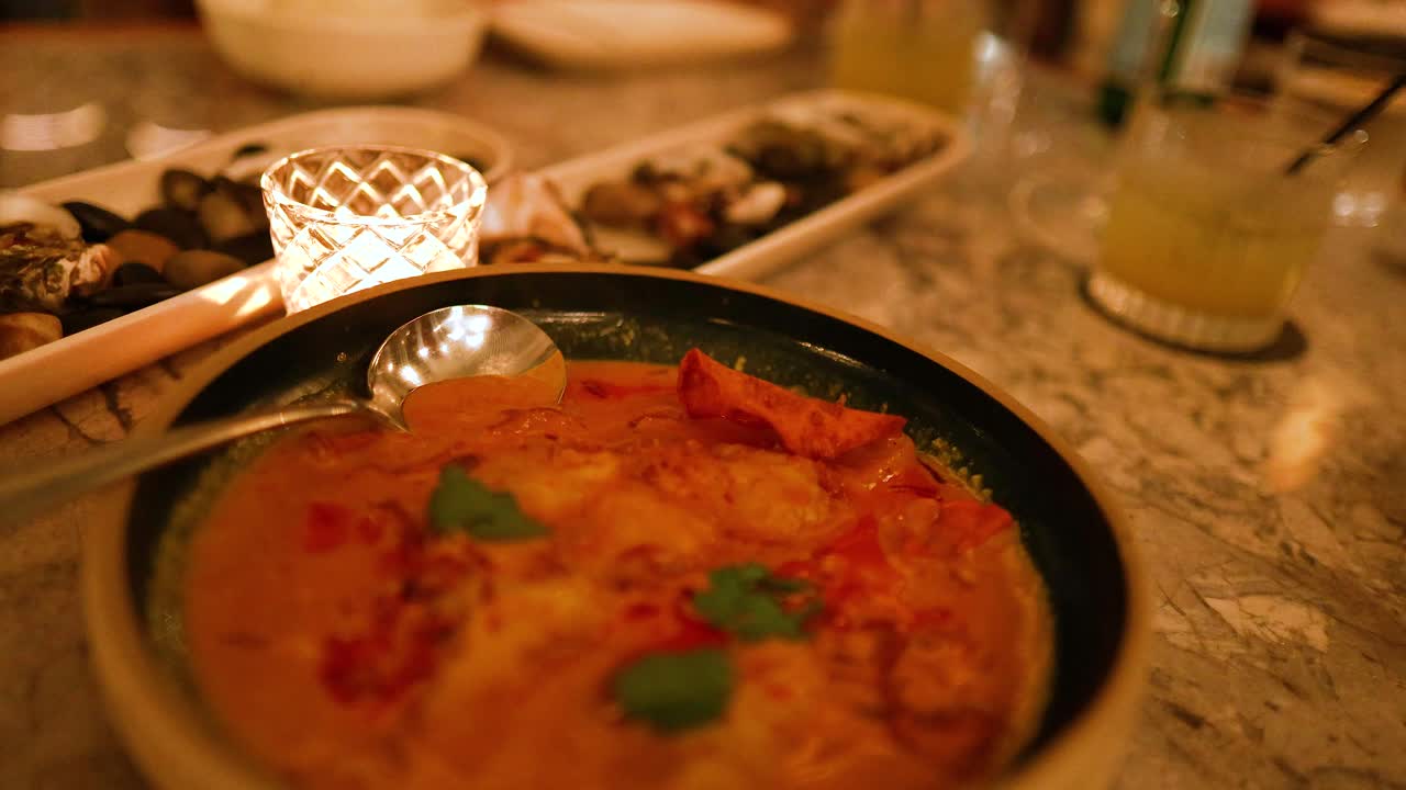 A warm, inviting scene of a curry dish under candlelight. The ambiance is intimate with soft lighting and a relaxed atmosphere