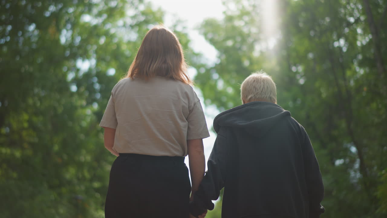 Sunlit Forest Walkway Woman And Child Slow Supportive Walk Under Trees, Soft Backlight Filtering Through Canopy, Holding Hands And Sharing Quiet Moment, Tender Bond And Calm Mood, Warm Afternoon