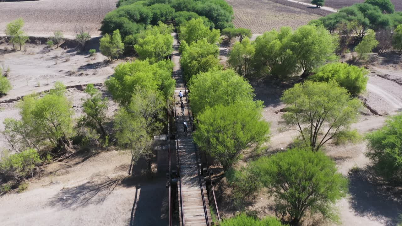 grupo de amigos montando en bicicleta cruzando un viejo puente a través de un paisaje increíble, disparo de drones