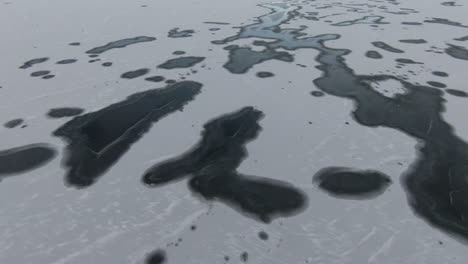 Dolly-Looking-down-at-dark-spots-and-patterns-on-frozen-lake