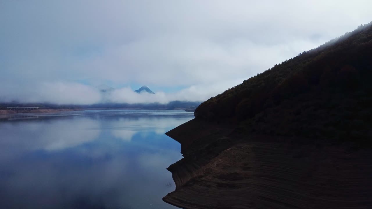 paisaje panorámico de montaña y lago que refleja un cielo azul nublado