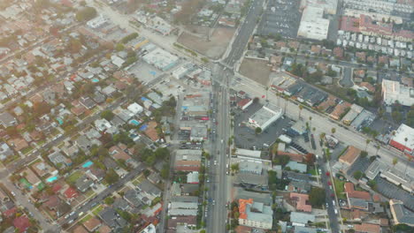 Antena:-Calle-Muy-Transitada-Con-Autos-En-Venecia,-California-Con-Palmeras-A-La-Luz-Del-Sol,