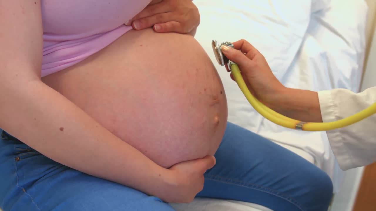 Doctor using a stethoscope on a pregnant womans stomach