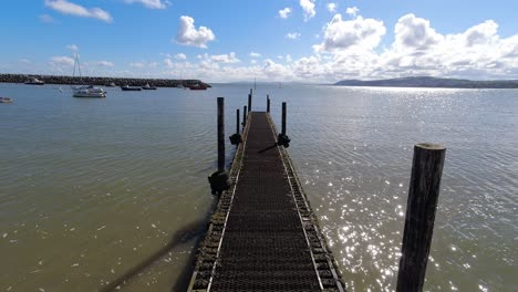 Shimmering-ocean-blue-sky-tranquillity-time-lapse-wooden-jetty-seascape-coastline-view