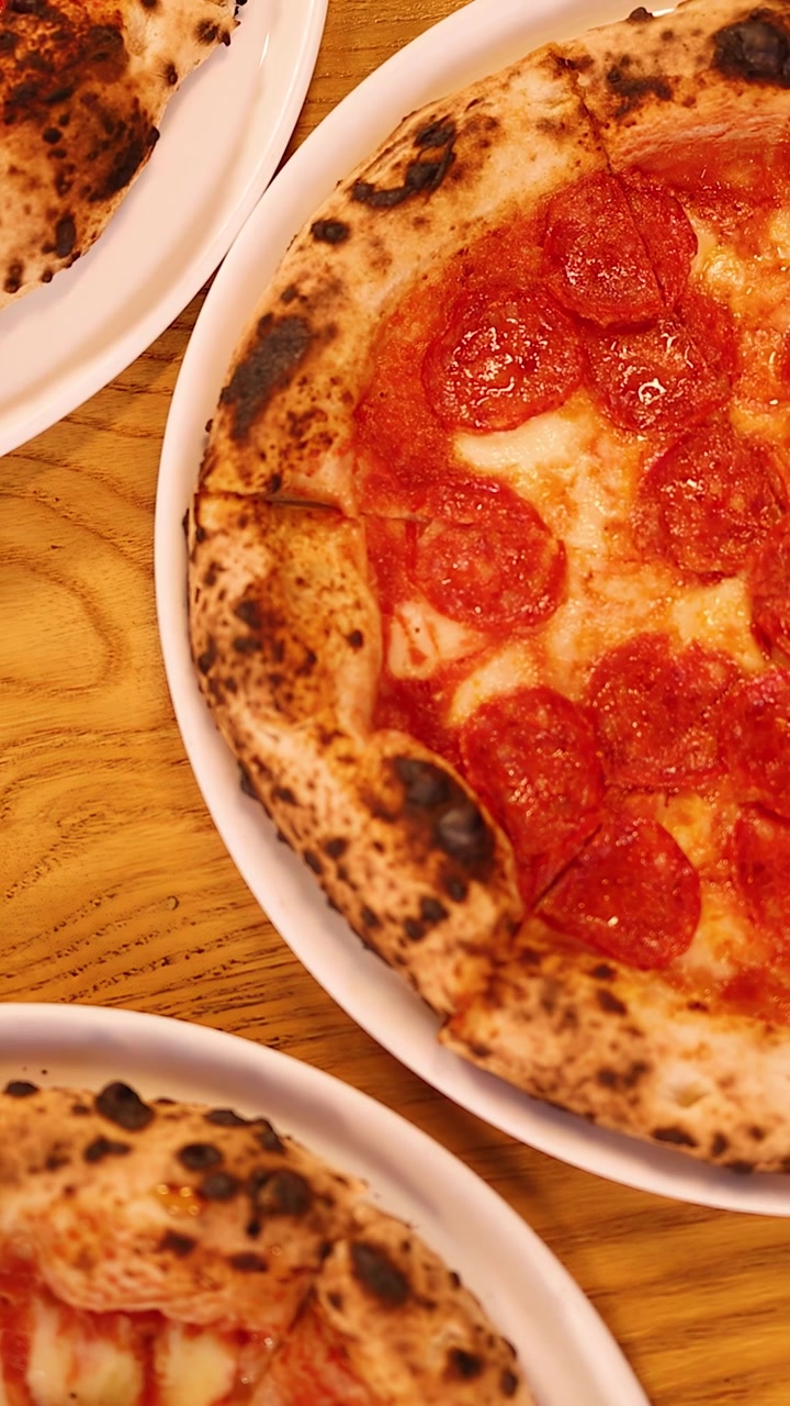 Una panoramica dall'alto della telecamera su un tavolo da ristorante con pizza napoletana, tagliere di formaggi e vino