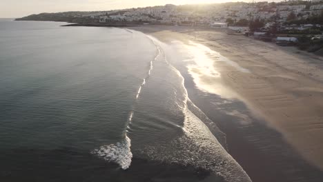 calm waves roll on shimmering praia da luz shoreline, algarve