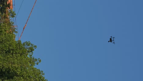 vertical: a commercial drone flying over the trees in urban area during an event