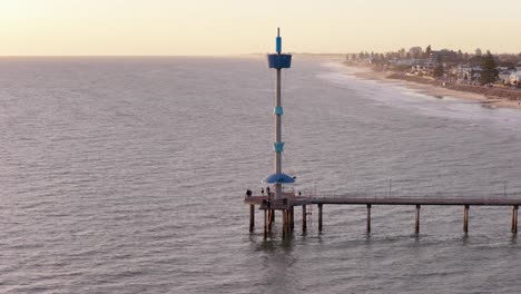 cinematic aerial orbit of brighton beach jetty tower with golden sunlight, adelaide, south australia