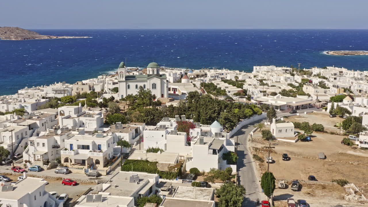 naousa paros grecia antena v2 sobrevuelo bajo pequeño pueblo capturando la iglesia faneromeni rodeada de hermosos edificios costeros encalados con la cima de la colina del parque paros en el fondo - septiembre de 2021