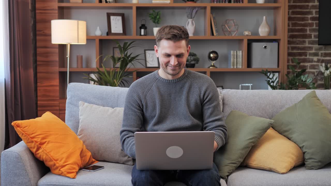un joven usando una computadora portátil, escribiendo, desplazándose, navegando por la web, mirando la pantalla.